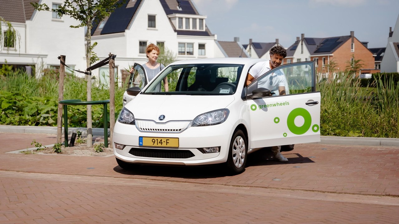 Zwei Menschen, die in ein Greenwheels-Carsharing-Auto in einer Wohnstraße einsteigen